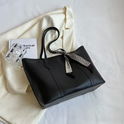 Black handbag with a decorative ribbon on a white surface