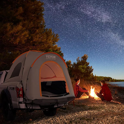 Two people sitting by a campfire next to a Vevor tent under a starry sky.