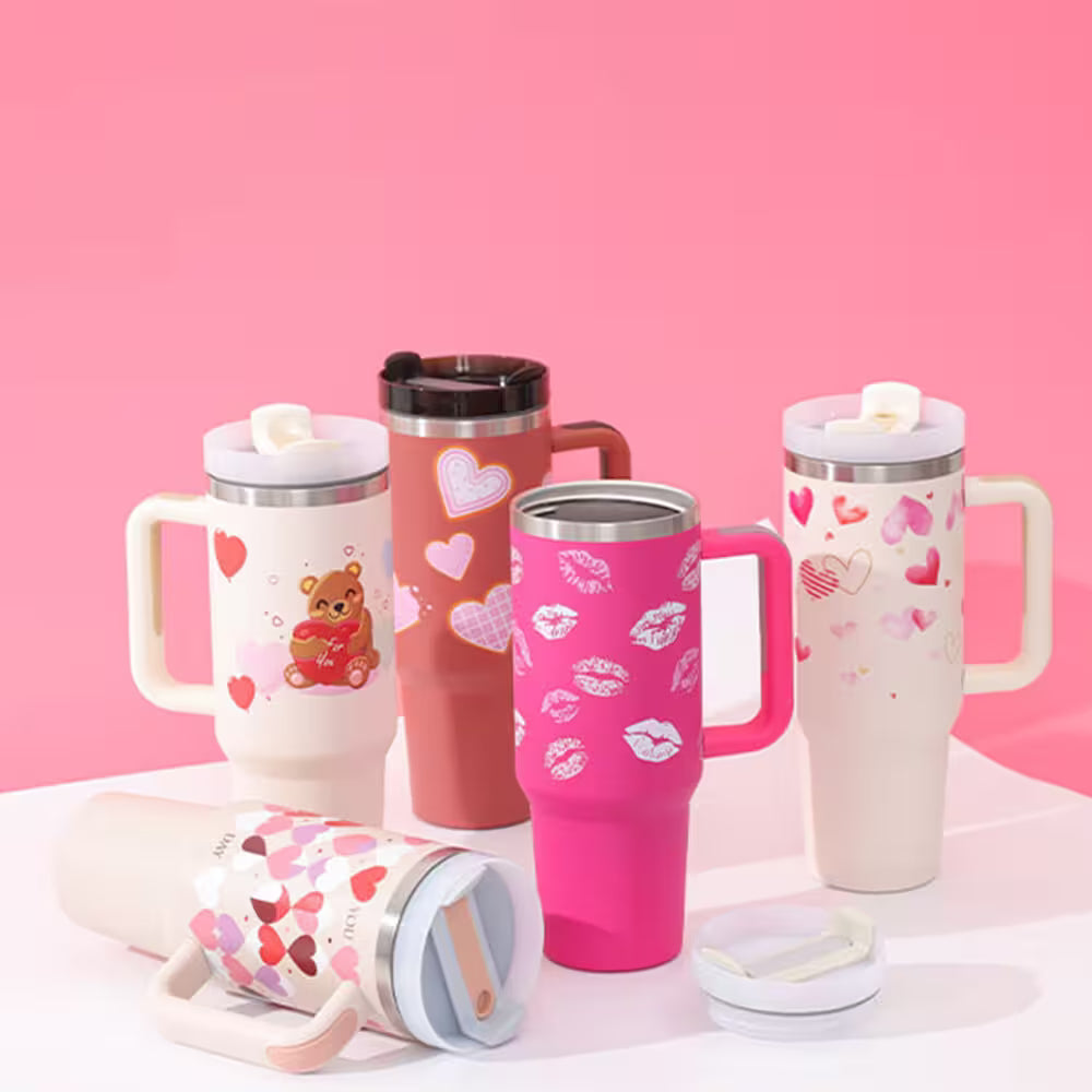Set of colorful travel mugs with various designs on a pink background