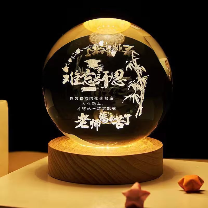 Glowing crystal ball with engraved text and bamboo design on a wooden base.