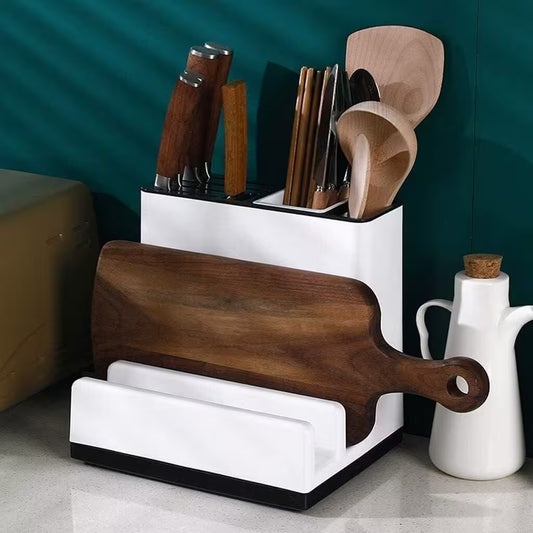 Kitchen utensil holder with cutting board, knives, and spoons against a teal wall.