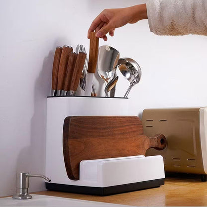 White kitchen utensil holder with wooden cutting board and utensils on a countertop.