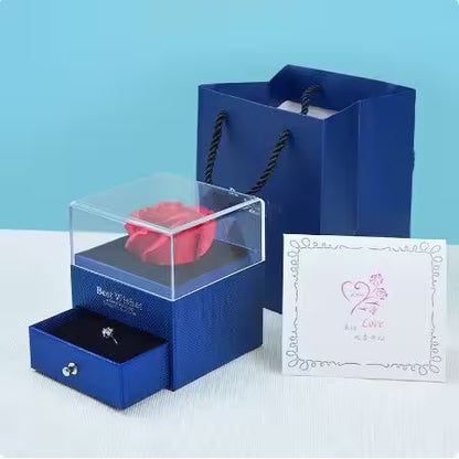 Blue gift box with a pink rose and card on a light blue background