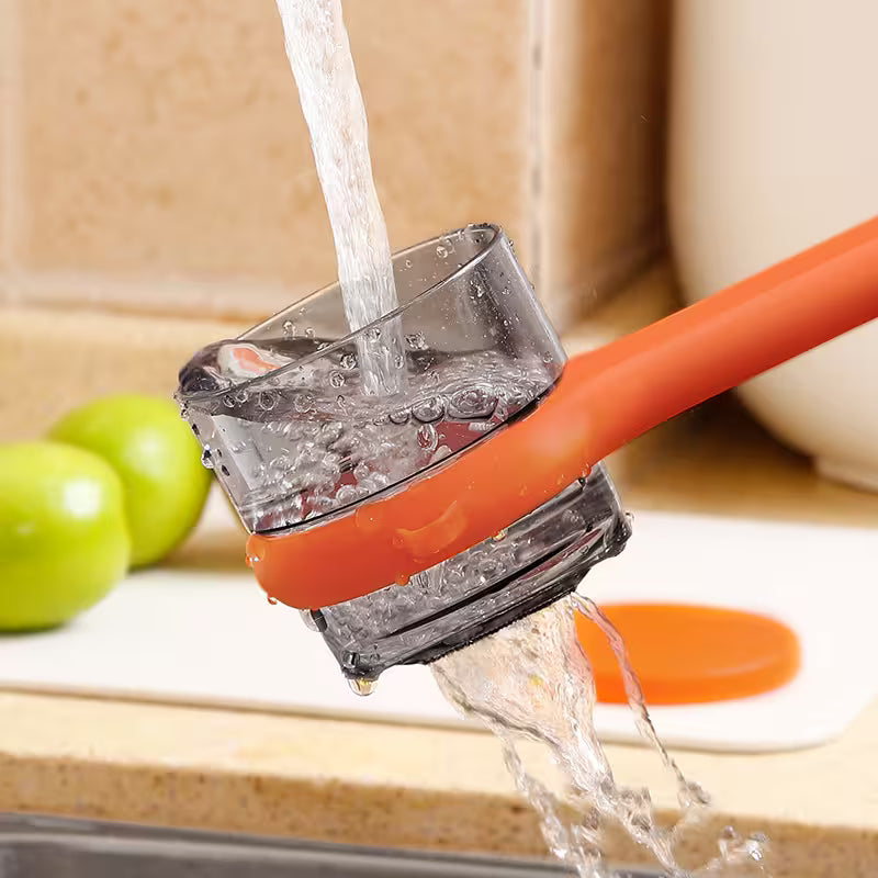 Orange kitchen tool with water flowing out, surrounded by green apples on a wooden surface.