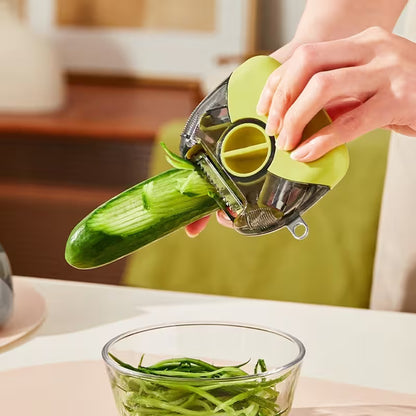 Person using a green vegetable peeler to shred a cucumber over a glass bowl on a kitchen counter.