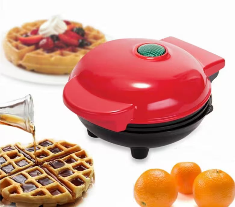 Red waffle maker with waffles and oranges on a white background