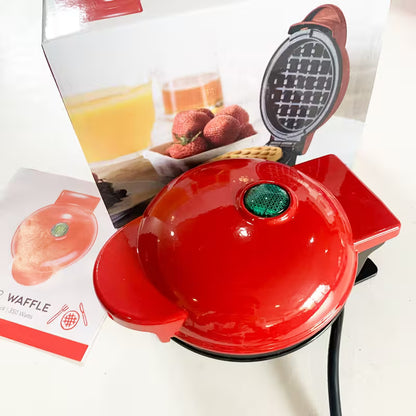 Red waffle maker with a green button on a white surface, accompanied by a recipe card.