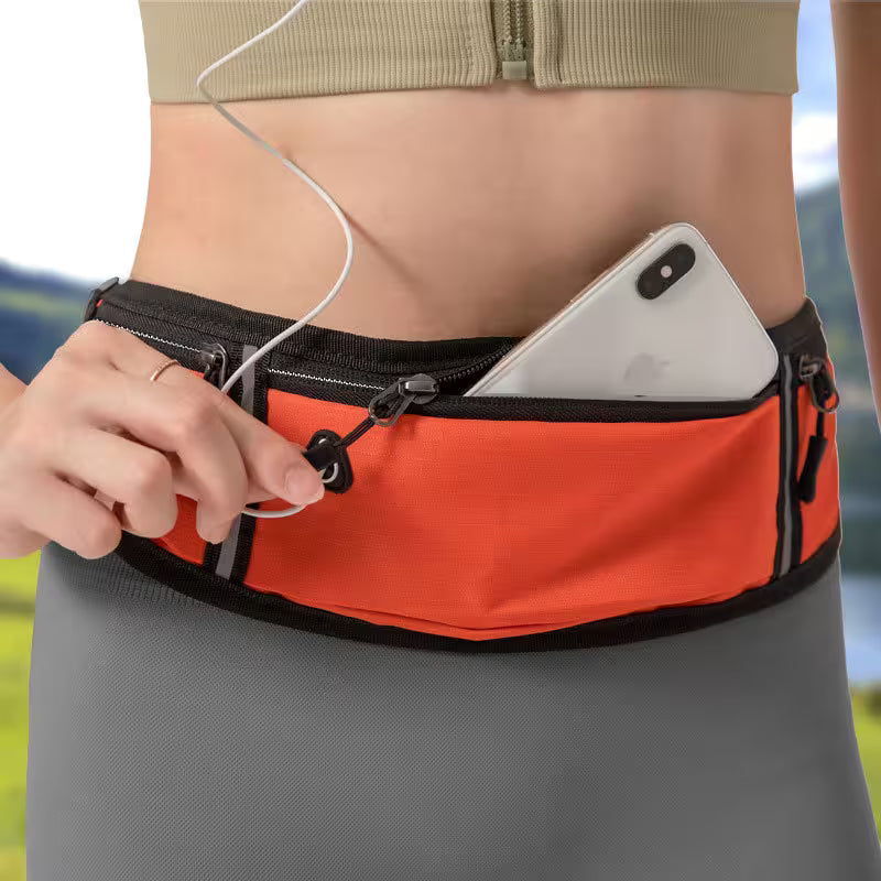 Person wearing an orange waist bag with a phone and earphones, outdoors.