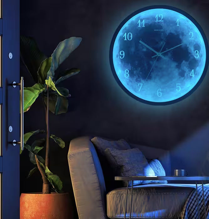 Wall clock with moon design glowing in a dark room