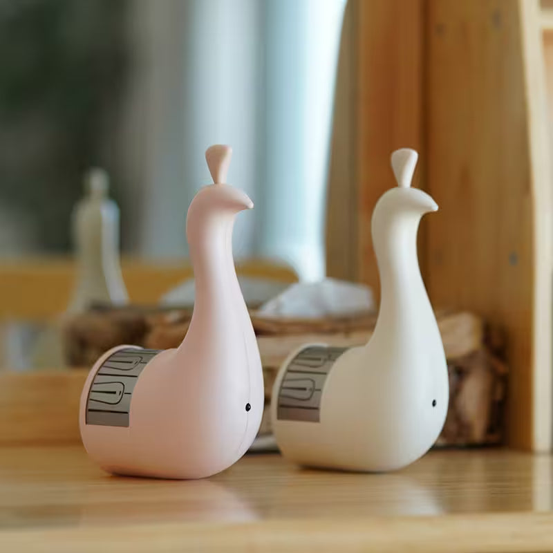 Two ceramic goose-shaped objects on a wooden surface with a blurred background