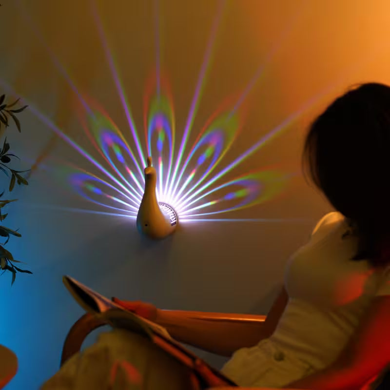 Peacock-shaped lamp projecting colorful light patterns on a wall with a person sitting nearby.