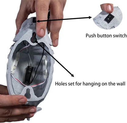 Close-up of a helmet with cutaway showing a push-button switch and holes for hanging on a white background.