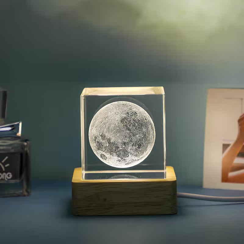 Moon-shaped object in a clear cube on a wooden base against a dark background