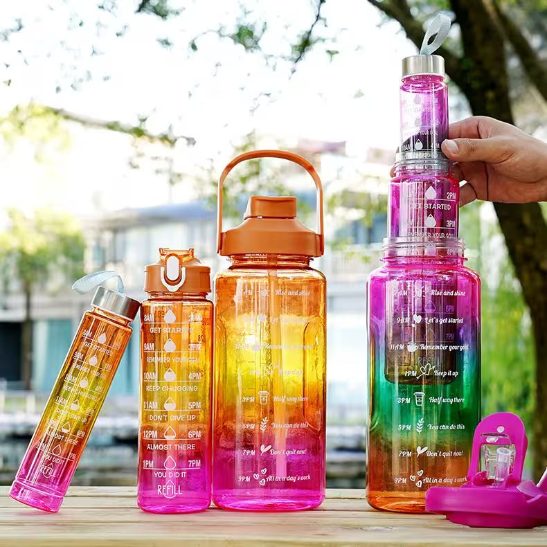 Colorful water bottles with measurement markings on a wooden surface outdoors.