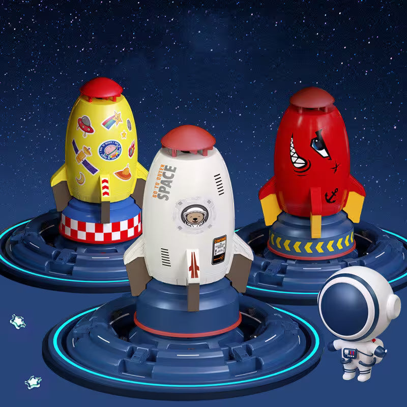 Three colorful toy rockets on blue bases with a small astronaut figure in front, set against a starry night sky.