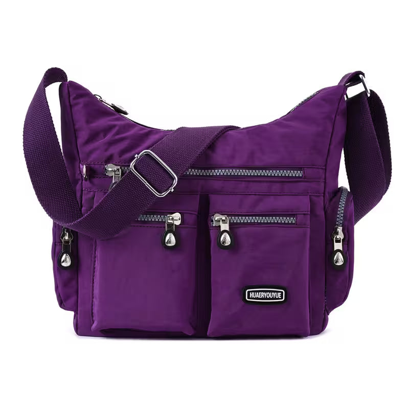 Purple shoulder bag with multiple zippers on a white background