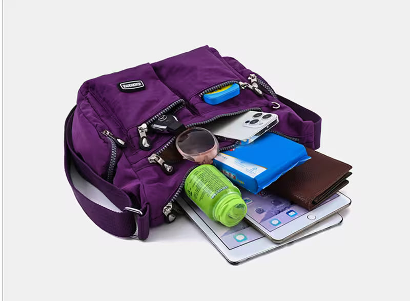Purple backpack with various items including a phone, wallet, and water bottle on a white background