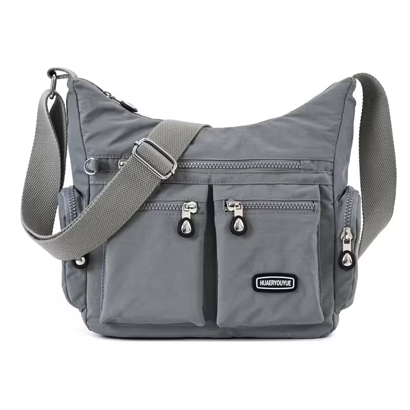 Gray shoulder bag with multiple pockets and zippers on a white background