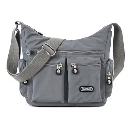 Gray shoulder bag with multiple pockets and zippers on a white background
