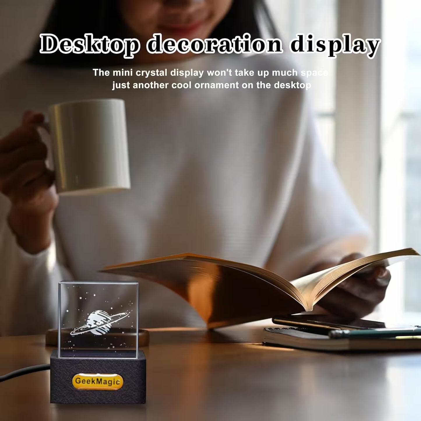 Person reading a book with a crystal display on a desk, featuring the brand 'GeekMagic'.