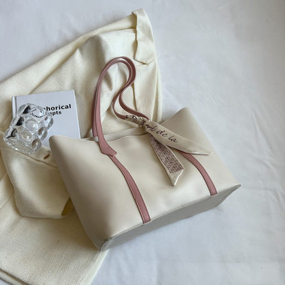 Beige handbag with pink strap on a white surface