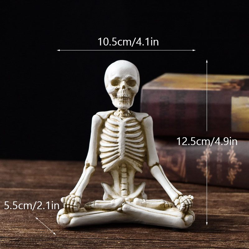 Miniature skeleton figurine in a meditative pose with measurements on a dark background