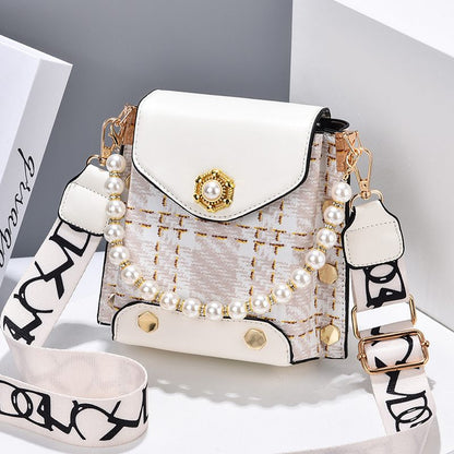 White handbag with pearl embellishments and a decorative strap on a light gray background