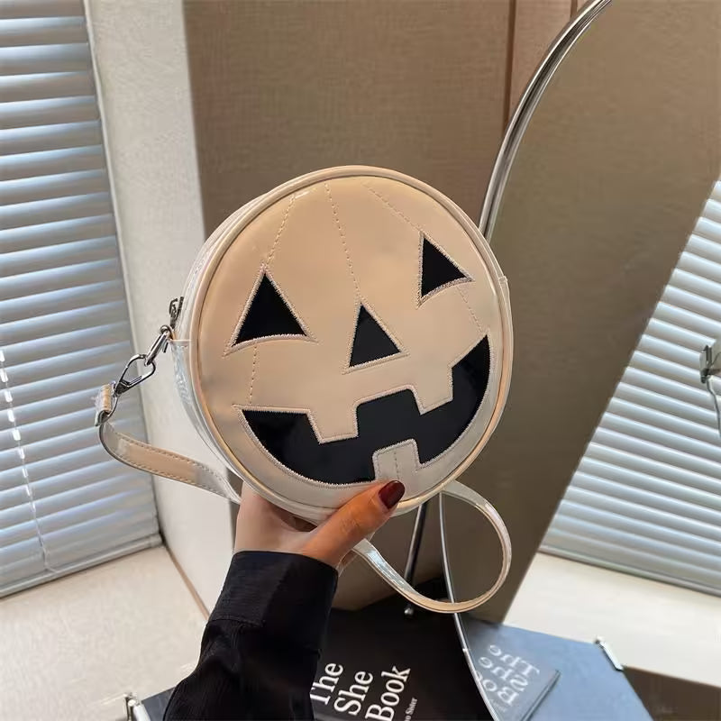 Round beige bag with black jack-o'-lantern face design held by a hand.