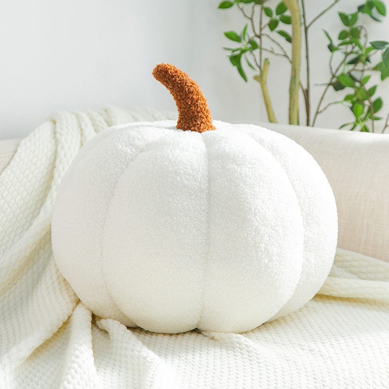 White pumpkin-shaped pillow with a brown stem on a white blanket
