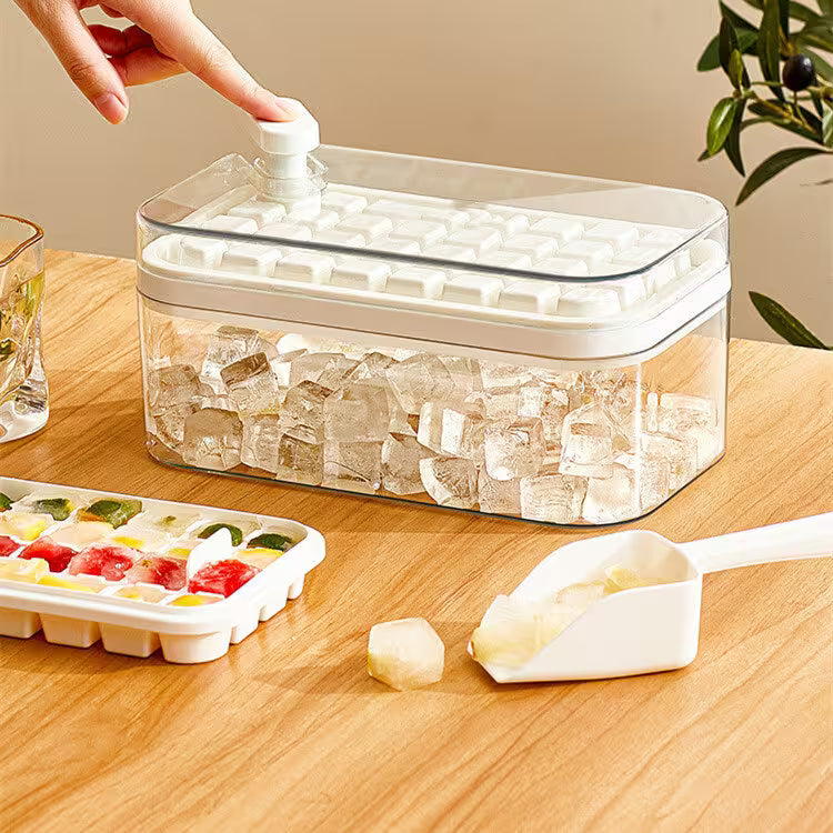 Clear ice cube tray with lid, ice cubes, and a scoop on a wooden surface.