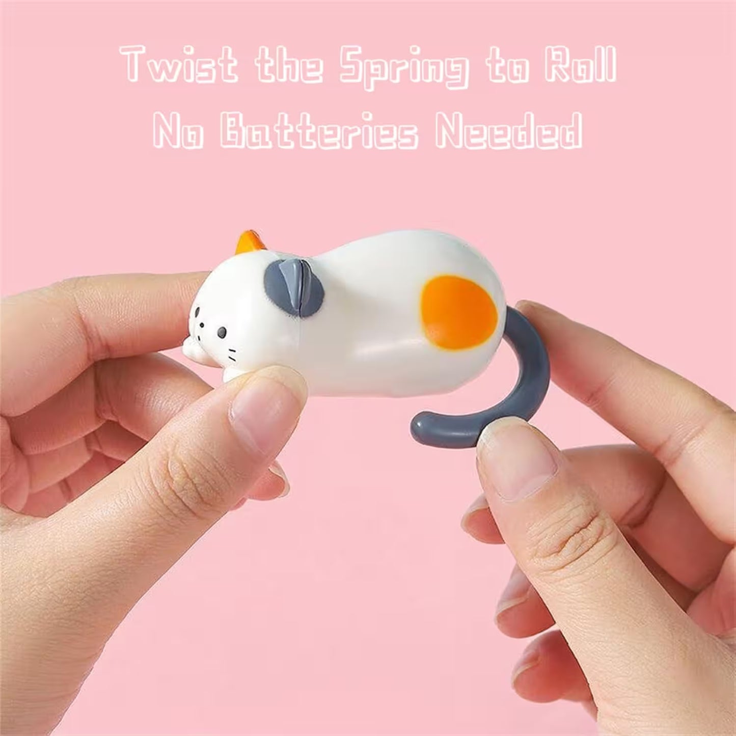 Toy figure of a cat with a spring mechanism held by hands against a pink background