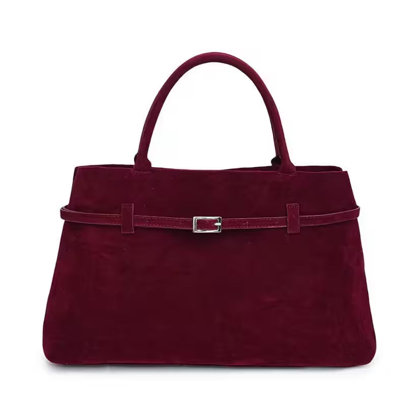 Maroon handbag with a belt and buckle on a white background