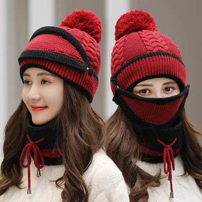 Red and black knitted hat with pom-pom and face mask worn by a model against a neutral background