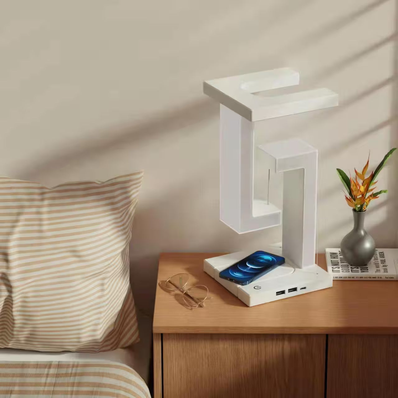 White LED desk lamp on a wooden nightstand with a plant and glasses in the background.