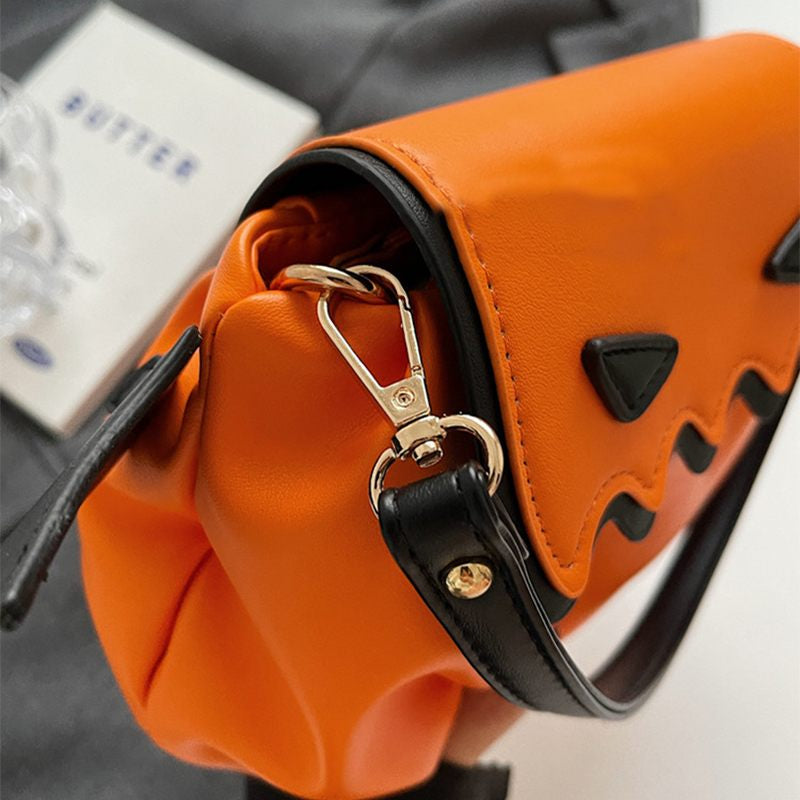 Close-up of an orange handbag with black accents and a gold clasp.