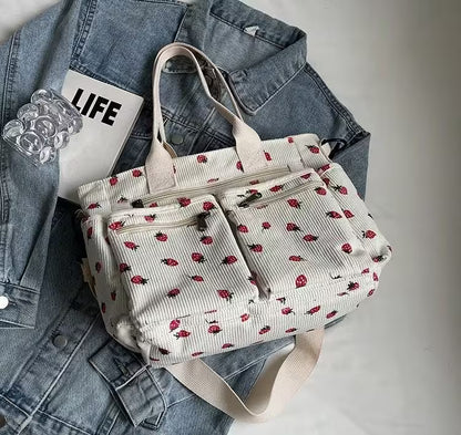 White tote bag with red floral pattern on a denim jacket