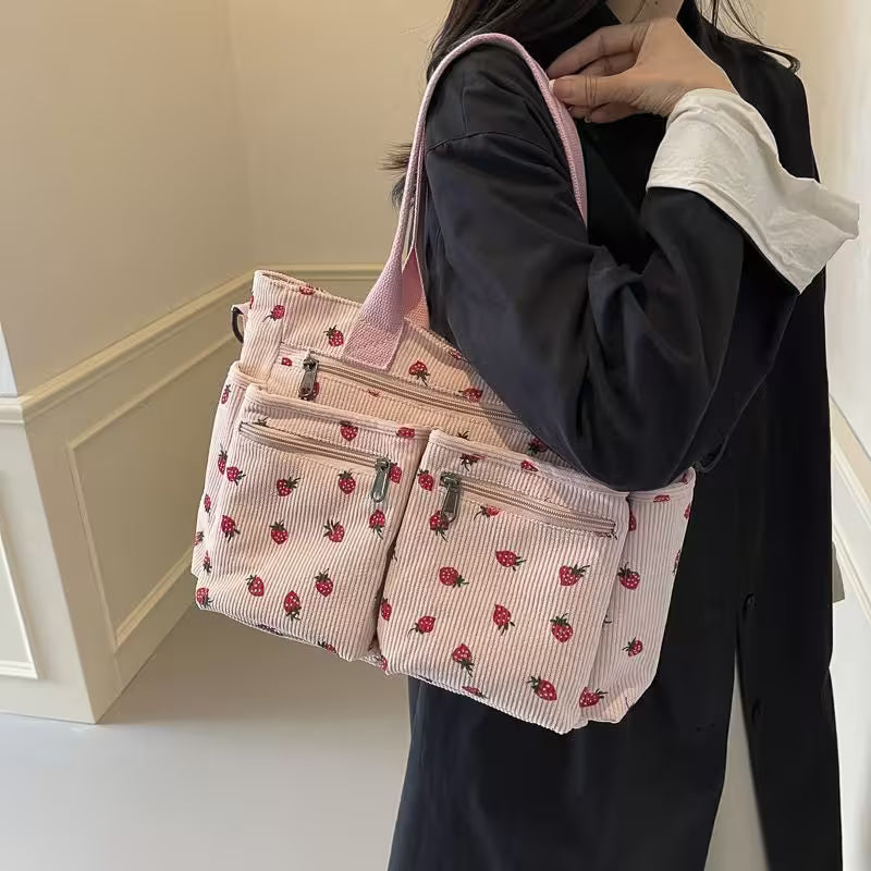 Person holding a pink tote bag with strawberry pattern