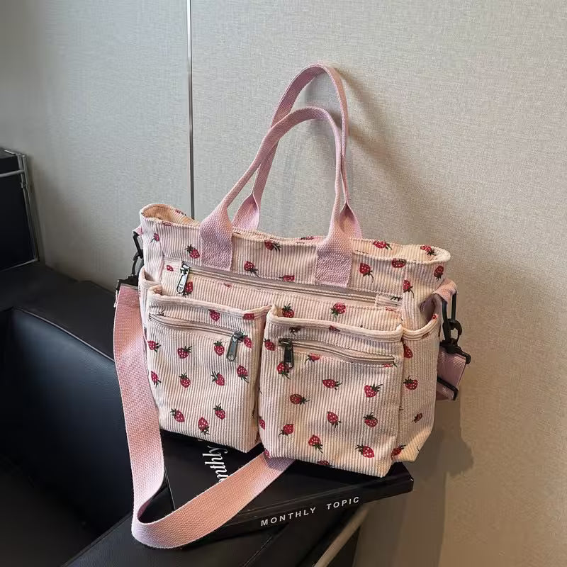 Pink patterned tote bag with multiple pockets on a gray surface