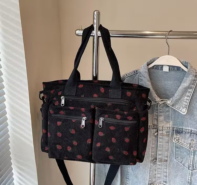 Black patterned bag hanging on a rack with a denim jacket next to it.