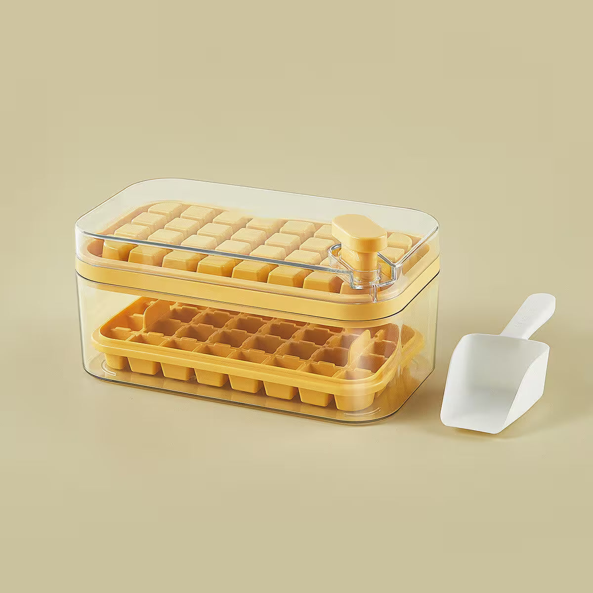 Yellow ice cube tray with clear lid and white scoop on a beige background